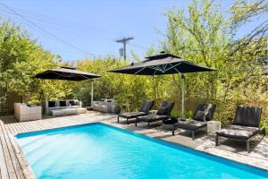 a swimming pool with chairs and umbrellas next to at The Pines Men-Only Stay in Fire Island Pines