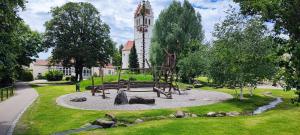 ein Spielplatz in einem Park mit einem Uhrenturm im Hintergrund in der Unterkunft Antony Home Ferienwohnung in Ostrach