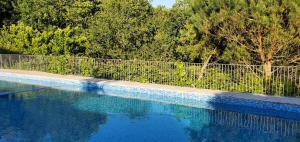 uma piscina ao lado de uma cerca e árvores em Quinta do Fontão - Casa com piscina em Arcos de Valdevez