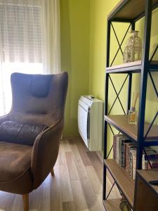 ein Wohnzimmer mit einem Stuhl und einem Bücherregal in der Unterkunft Cozy Stay Apartment in Tirana