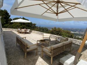 a patio with two chairs and an umbrella at Trulli della Chiesetta in Selva di Fasano