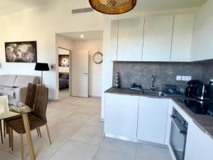 a kitchen with white cabinets and a table and a dining room at Panoramic Sea View Appartment Blue Pearl in Nice