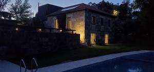 uma casa de pedra com uma piscina em frente em Quinta do Fontão - Casa com piscina em Arcos de Valdevez