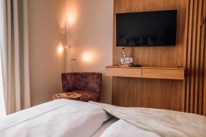 um quarto de hotel com uma cama e uma cadeira e uma televisão em Schmidtburger Hof em Weiler