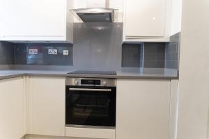 a kitchen with white cabinets and an oven at 4 Bed House - Sleeps 8 - HotTub - Garden - Parking in Milton Keynes