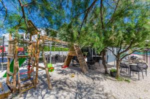 ein Spielplatz im Sand mit Bäumen und Stühlen in der Unterkunft Apartments Jadranka in Grebaštica