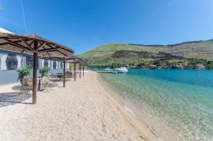 ein Strand mit Stühlen und Sonnenschirmen direkt am Wasser in der Unterkunft Apartments Jadranka in Grebaštica