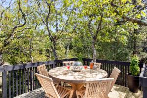 a table and chairs on a deck with trees at Fire Island Pines Rooms in Fire Island Pines