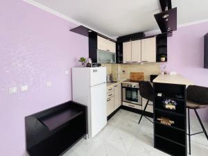 cocina con paredes moradas y nevera blanca en Sea View Rental Iglika Apartments en Golden Sands