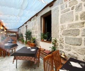 um restaurante com mesas e cadeiras e uma parede de pedra em HOTEL EL RASTRO - Palacio Duque de Tamames - em Ávila
