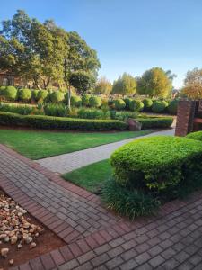 a brick walkway in a garden with bushes and trees at Lions Haven in Pretoria