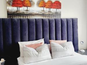 a bed with two pillows and a painting of trees at Lions Haven in Pretoria