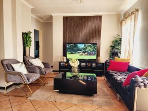 a living room with a couch and chairs and a tv at Lions Haven in Pretoria