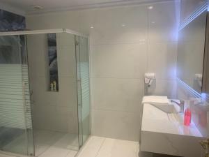 La salle de bains blanche est pourvue d'une douche et d'un lavabo. dans l'établissement Luxurious 4 Bedroom Villa in Abdoun-Amman, à Amman