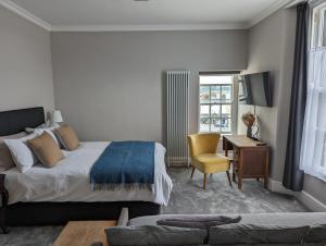 a bedroom with a bed and a desk with a chair at The Chelsea in Llandudno