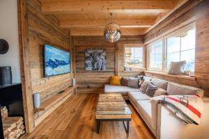 - un salon avec des murs en bois et un canapé dans l'établissement Filzsteinresort Chalets Chalet Bergankunft 236, à Krimml