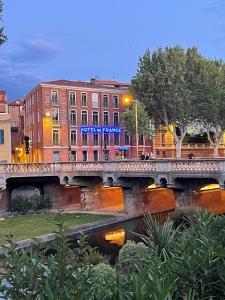 a bridge over a river in front of a building at Hotel De France in Perpignan