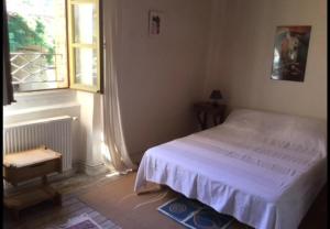 1 dormitorio con cama blanca y ventana en Maison de 2 chambres avec piscine partagee jardin clos et wifi a Massaguel, en Massaguel