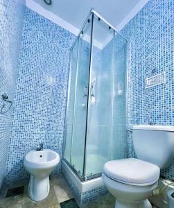 uma casa de banho em azulejos azuis com um WC e um chuveiro em Mirage Mer B&B em Catânia