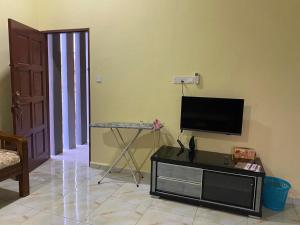 a living room with a flat screen tv and a table at Homestay BONDA 2 in Pasir Mas
