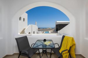a table and chairs in a room with a window at Montrez Santorini - 2 Bedroom Apartment in Mesaria