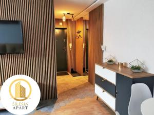 a room with a tv and a desk with a dresser at Apartament Lancelot in Tychy