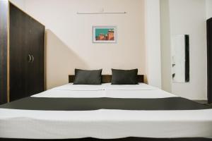 - une chambre avec un grand lit blanc et des oreillers noirs dans l'établissement OYO NAZ GUEST HOUSE, à Jalandhar