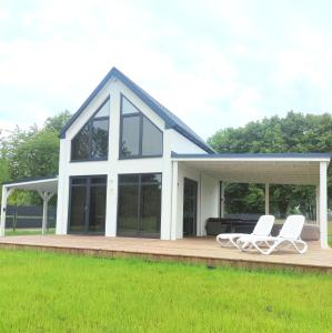 une maison avec deux chaises blanches sur une terrasse dans l'établissement Ferienhaus Laura 70qm bis 5 Gäste mit Fass-Sauna, Whirlpool April bis Oktober, 75qm Terrasse und eingezäunten Garten Haustiere willkommen, à Sierosław