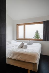 una camera da letto con un grande letto bianco e una finestra di CASA LUMNEZIA - Panoramic Ecodesign Apartment Obersaxen - Val Lumnezia I Vella - Vignogn I near Laax Flims I 5 Swiss stars rating a Vella