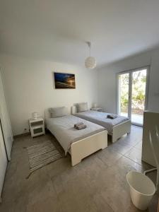 - une chambre blanche avec 2 lits et une fenêtre dans l'établissement Casa Sognu di Orizonte, à Figari