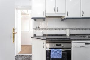 a white kitchen with white cabinets and a stove at 3 Bdr Apt In Cornella 5 Mins Form The Metro in Cornellà de Llobregat +22 photos
