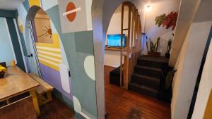 a living room with a hallway with a tv and stairs at La Embajada Hostel in San Cristóbal de Las Casas