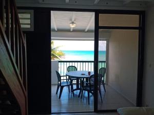 a dining room with a table and chairs and the ocean at Une terrasse pleine vue mer in Le Gosier +5 photos