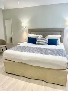 1 dormitorio con 1 cama grande con almohadas azules en Kyriad Saumur Hyper Centre Hôtel Appartements et SPA soins Sothys Paris, en Saumur