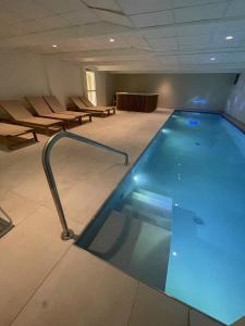 uma grande piscina num quarto com cadeiras em Kyriad Saumur Hyper Centre Hôtel Appartements et SPA soins Sothys Paris em Saumur