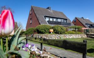 a house with a rock retaining wall and a yard at Sylter Meerholz in Tinnum