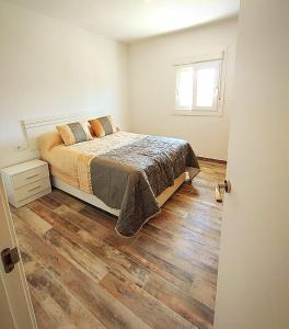 Un dormitorio con una cama y suelo de madera. en Casa natural 1, en Chiclana de la Frontera