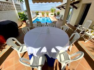 une table et des chaises blanches sur une terrasse avec piscine dans l'établissement Karma Villa with views by HLCLUB Agency, à Sant Pere de Ribes