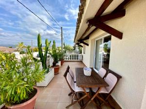 uma mesa de madeira e cadeiras numa varanda com plantas em Karma Villa with views by HLCLUB Agency em Sant Pere de Ribes