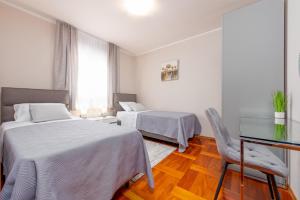 a bedroom with two beds and a table and a chair at Apartment Matea with terrace in Zadar