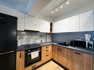 a kitchen with wooden cabinets and a black refrigerator at AD Apartments in Cluj-Napoca