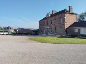 a large brick building with a grass yard in front of it at Gîte au Ptit Canin in Moyenneville