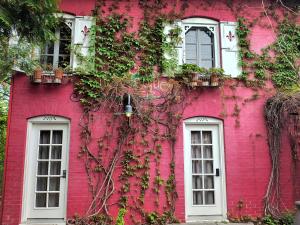 a pink building with white windows and vines at Le Mange Grenouille in Bic