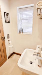 a white bathroom with a sink and a window at Wild Valley Bunkhouse in Llanrhaeadr-ym-Mochnant