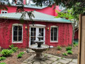 a red house with a fountain in front of it at Le Mange Grenouille in Bic