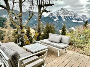 una terraza de madera con sofá, mesa y sillas en Gstaad Paradise View Chalet with Jacuzzi, en Rougemont