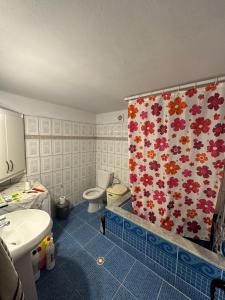 uma casa de banho com um WC e uma cortina de chuveiro com flores em Evelina Ernild Rooms em Saranda