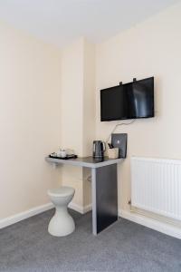 a room with a desk with a tv on the wall at The Well Inn in Shepton Mallet