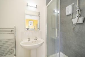 a white bathroom with a sink and a shower at The Well Inn in Shepton Mallet