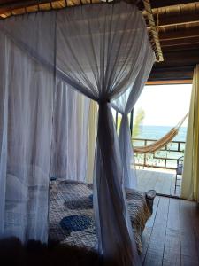 a canopy bed with a cat sitting in front of a window at Zakua Beach in Guachaca